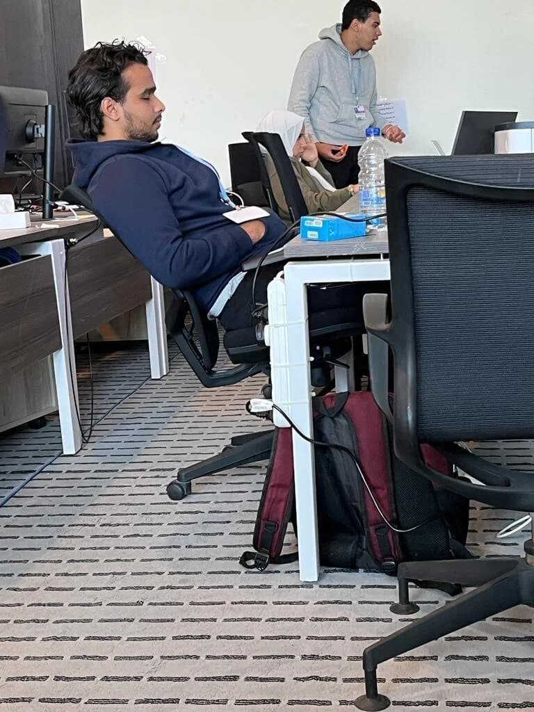 Ibrahim ( Ibra ) Gamal in office meeting with colleagues discussing work with laptop