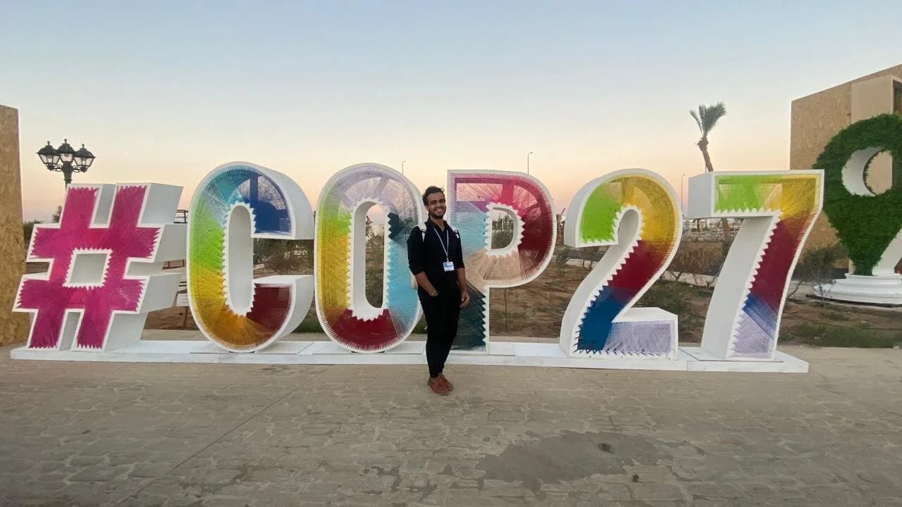 Ibrahim ( Ibra ) Gamal posing in front of colorful #COP27 sign at United Nations climate conference in Egypt